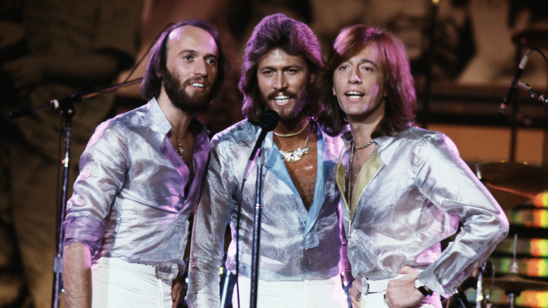 Maurice, Barry, and Robin Gibb performing in sheer mesh blue shirts on stage