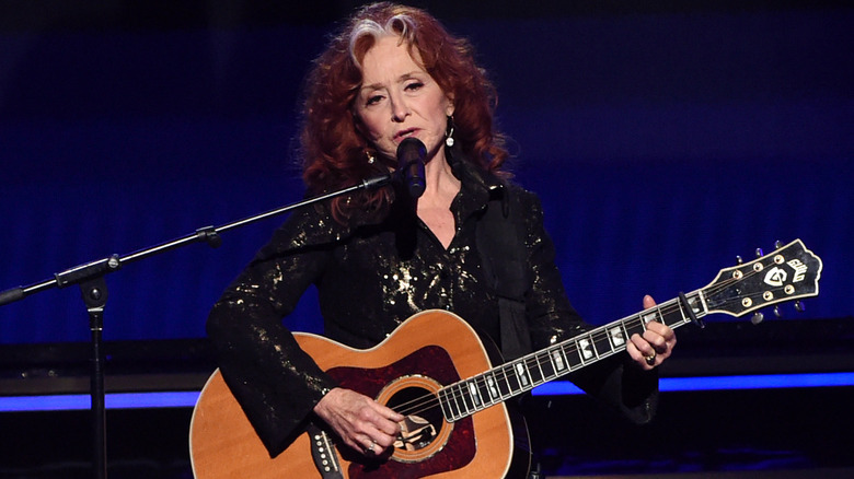 Bonnie Raitt playing an acoustic guitar and singing into a microphone at the 2020 Grammy awards