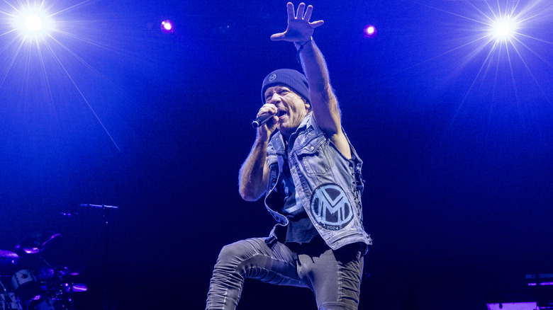 Bruce Dickinson singing and raising arm on stage