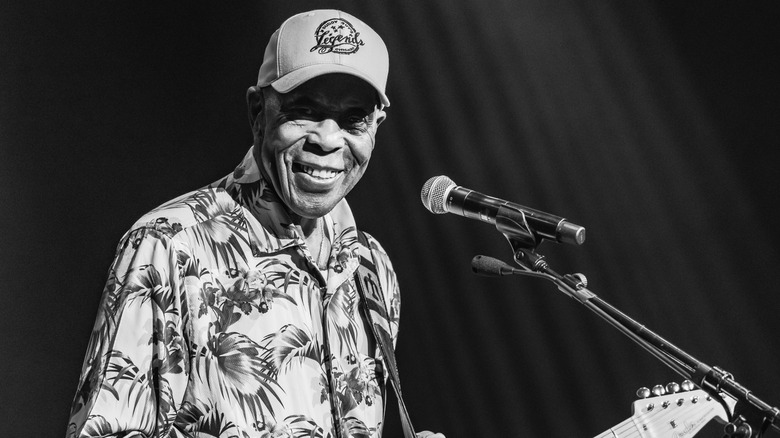 Buddy Guy smiling in cap with guitar on stage