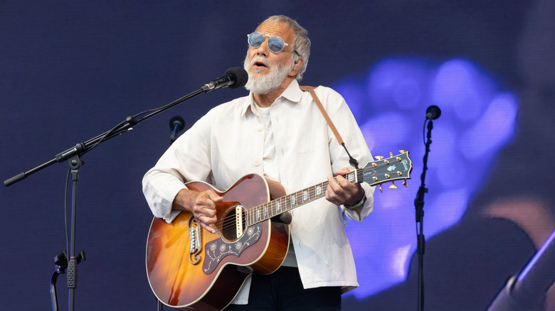 Yusuf Islam AKA Cat Stevens playing guitar and singing on stage.