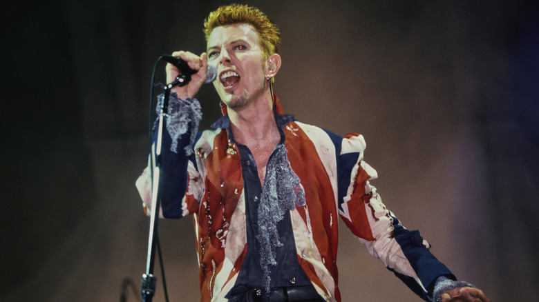 David Bowie in torn union jack shirt singing on stage