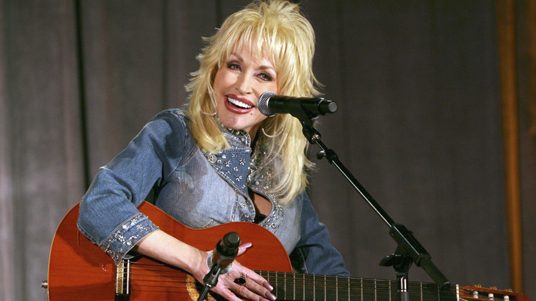 Dolly Parton sat smiling playing guitar