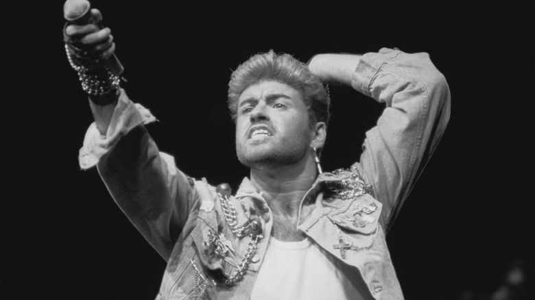 George Michael on stage holding his microphone to the crowd
