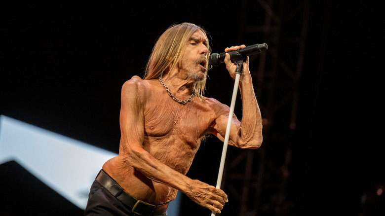 Iggy Pop singing shirtless into a microphone on stage