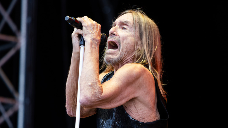Iggy Pop singing into a microphone on stage.