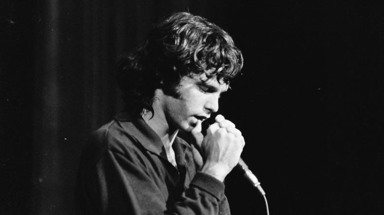 Jim Morrison singing into a microphone onstage in Philadelphia in 1967 with his eyes closed.