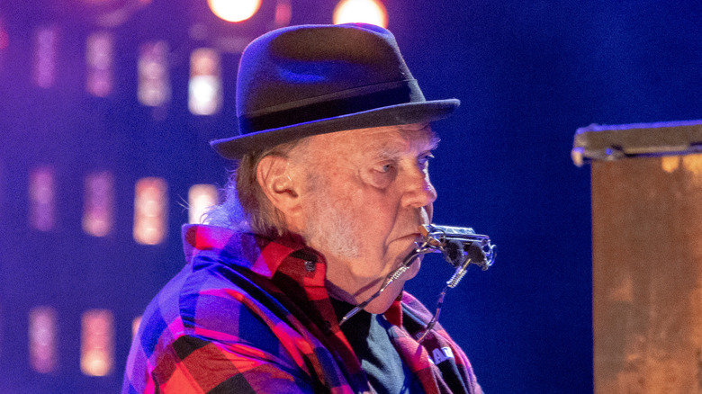 Neil Young playing piano and harmonica onstage
