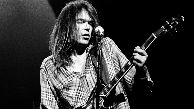 Neil Young playing guitar on stage