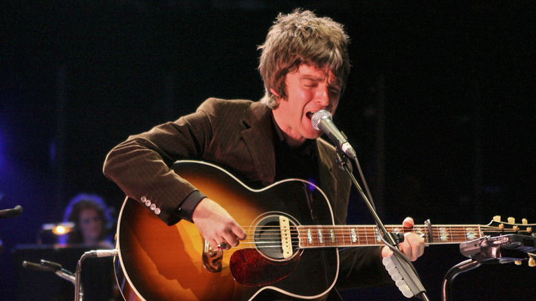 Noel Gallagher playing guitar and singing