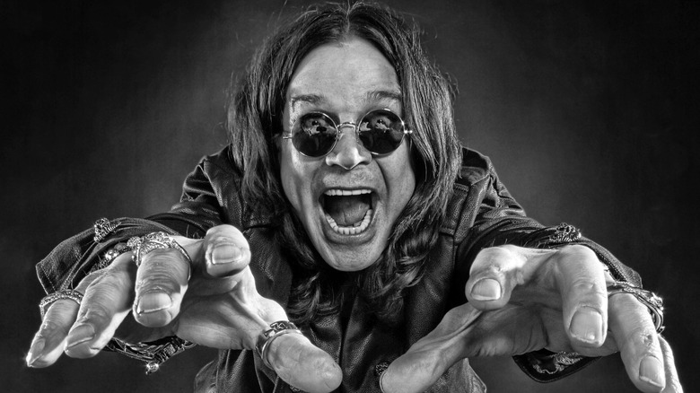 Ozzy Osbourne reaching hands toward camera smiling in sunglasses