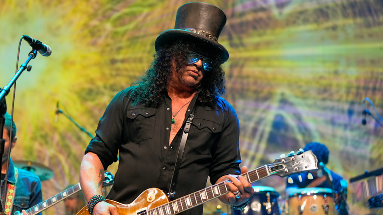 Slash playing guitar on stage in top hat