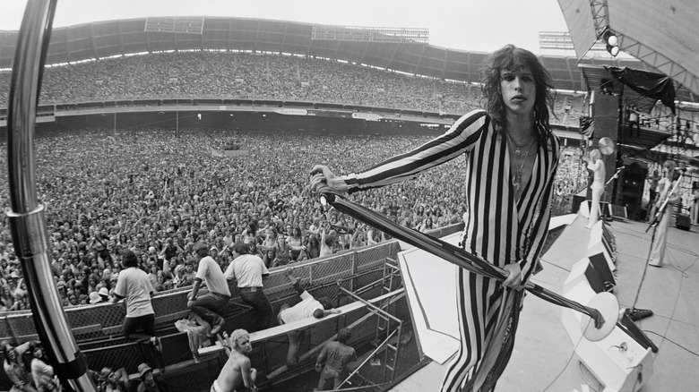 Fisheye photo of Steven Tyler standing in front of thousands of fans for a performance in the late '70s