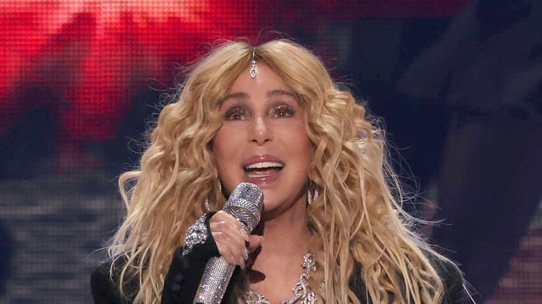 Cher holding microphone and singing onstage