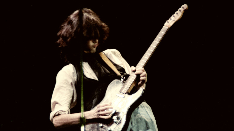 Jimmy Page on stage, soloing on his guitar.