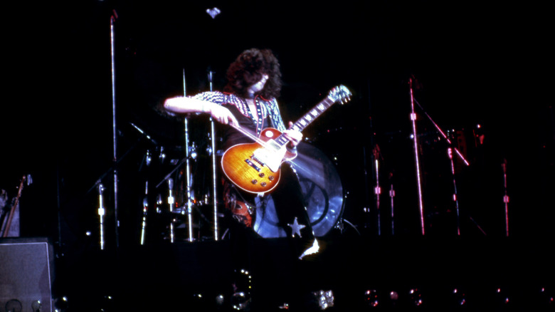 Jimmy Page on stage playing his guitar with a violin bow.
