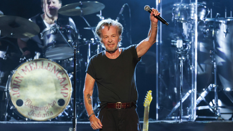 John Mellencamp holding his microphone in the air