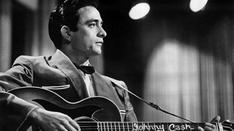 Young Johnny Cash in suit playing guitar
