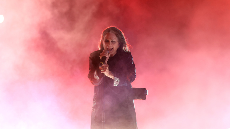 Ozzy Osbourne performs amid white smoke against red background
