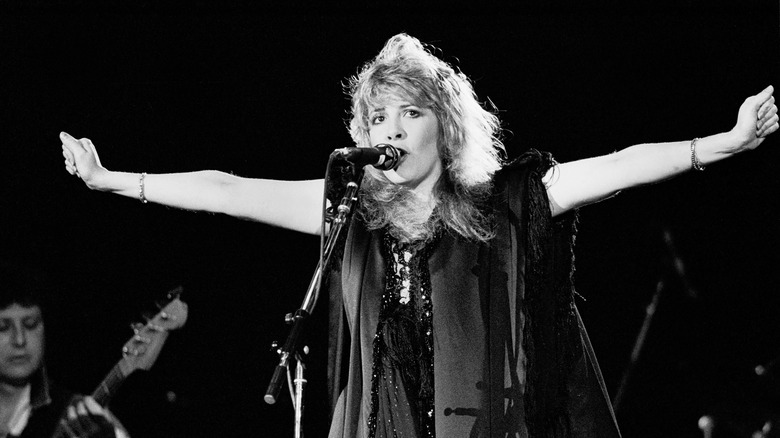 Stevie Nicks singing on stage with arms out