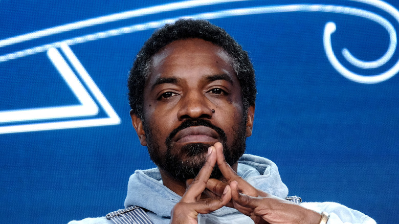 André 3000 beard hands together blue background