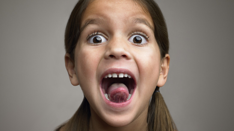 A young girl with her mouth open and tongue sticking out