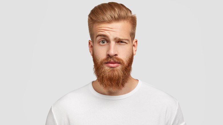 A bearded man with one eyebrow raised