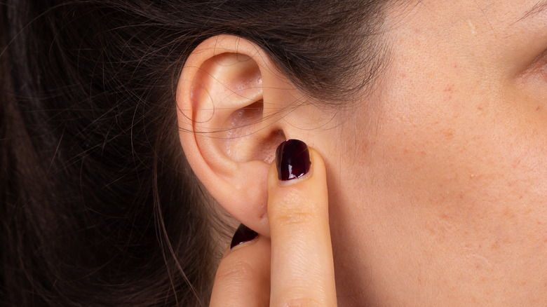 Closeup of woman pointing at her right ear