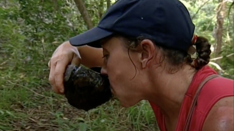 Survivor contestant drinking cup of well water