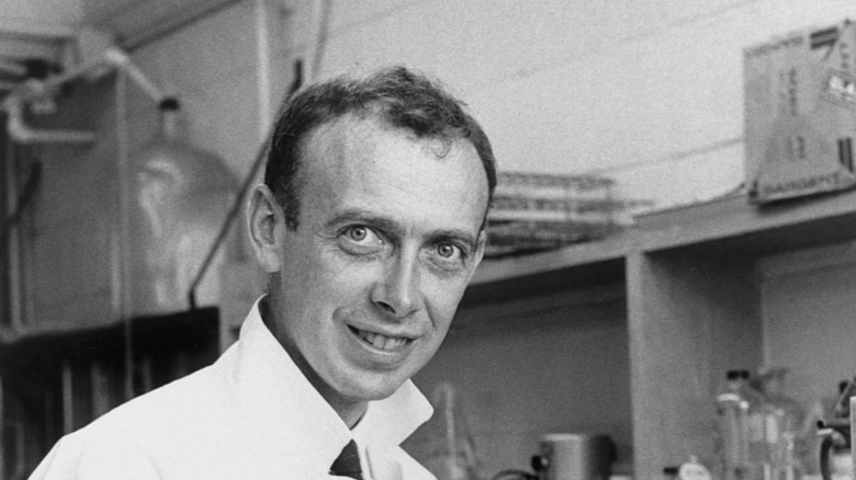 James Watson sitting in lab coat, 1962