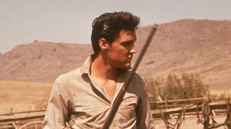 Elvis Presley outdoors holding gun