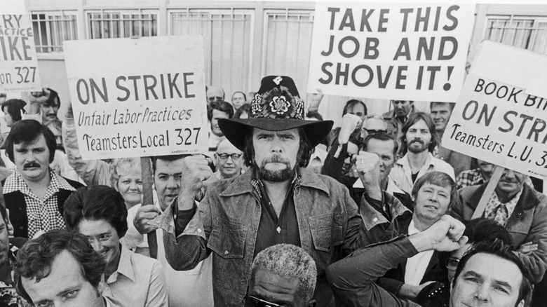 Johnny Paycheck standing in crowd of strikers with fists raised