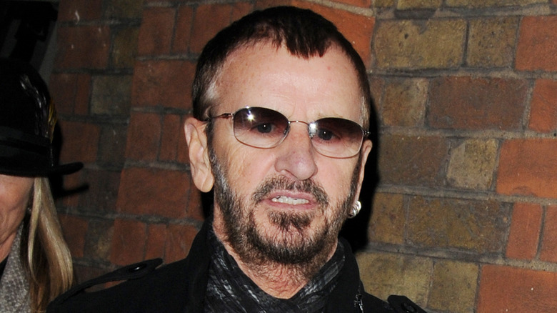 Ringo Starr grimacing in front of brick wall