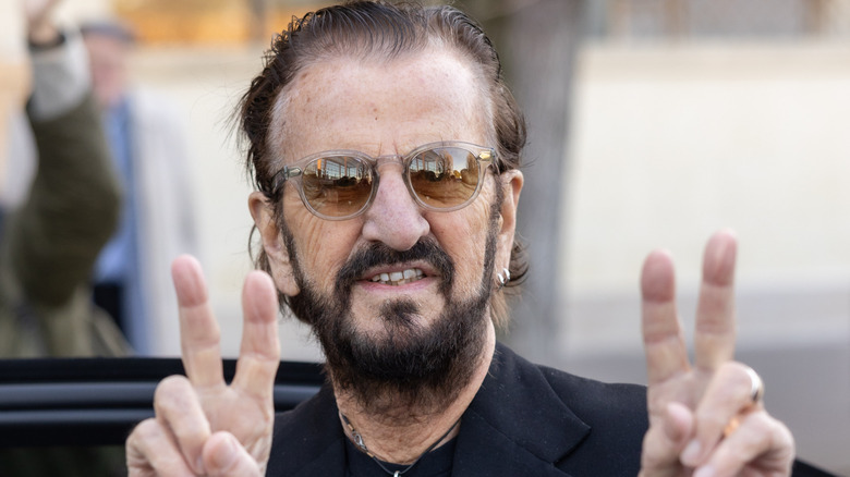 Ringo Starr smiling and doing peace signs