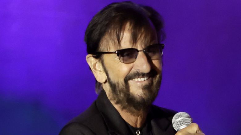Ringo Starr grinning with microphone on stage