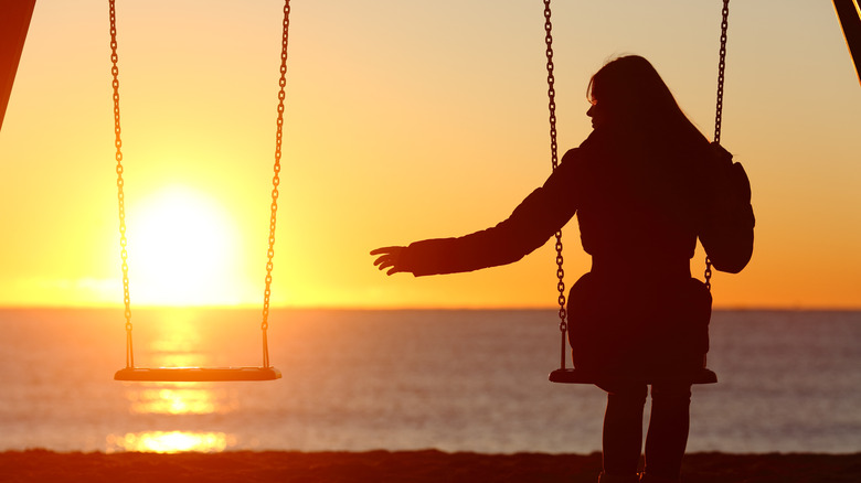 Woman on a wing at sunset reaching out for no one