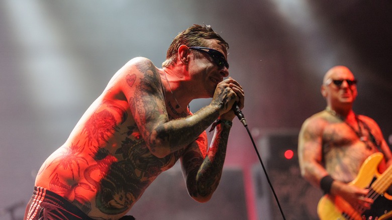 Sebastian Murphy of the Viagra Boys leaning into a microphone with red lights illuminating behind him during his Lollapalooza set in 2026