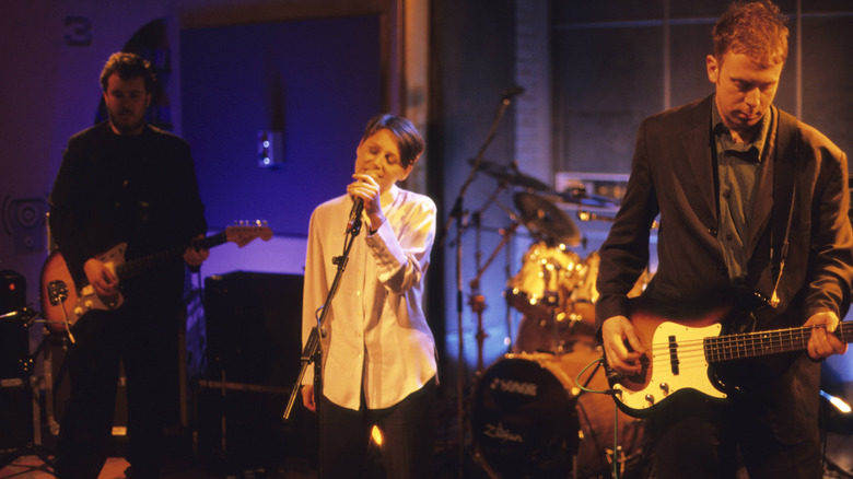 Cocteau Twins lined up on stage with orange and violet lighting while performing
