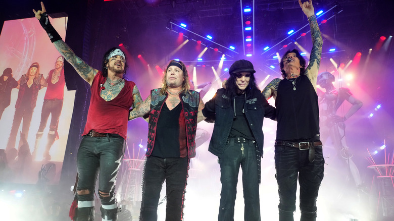 The members of Motley Crue on stage interacting with the audience.