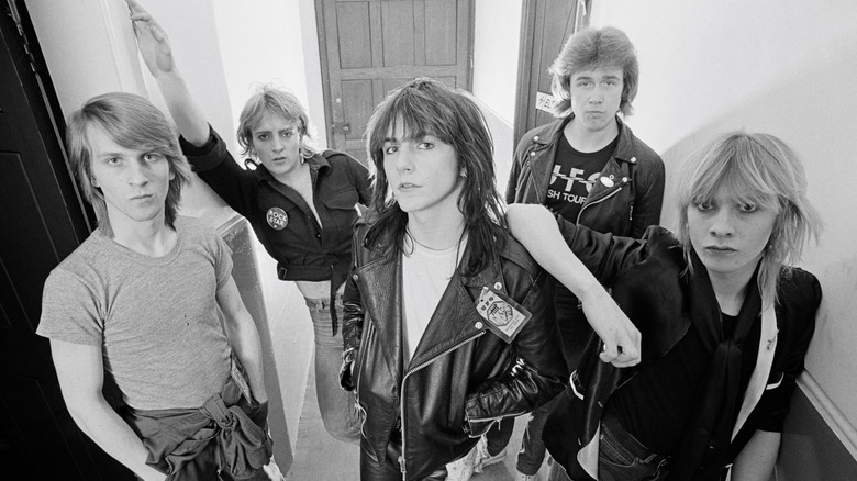 Original line-up Girl with Phil Collen in rock outfits posing in corridor