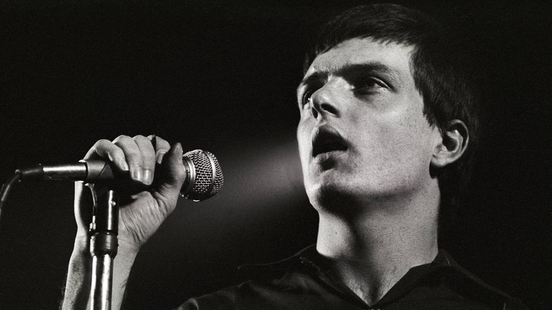Joy Division's Ian Curtis holding the mic on stage