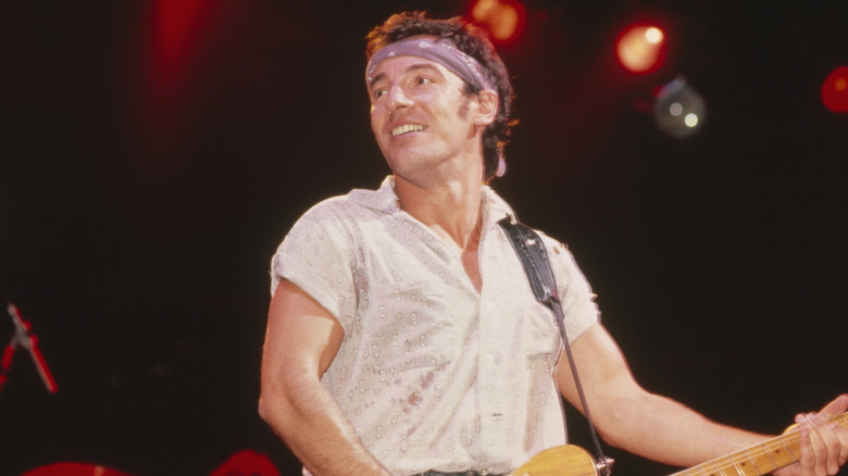 Bruce Springsteen playing guitar onstage and looking to side