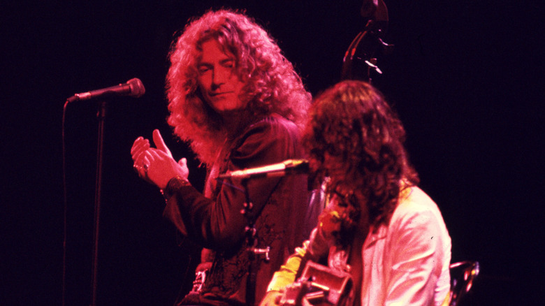 Robert Plant claps as Jimmy Page plays guitar in a Led Zeppelin concert