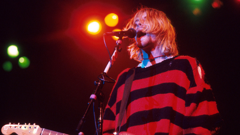 Kurt Cobain in striped shirt with guitar and microphone