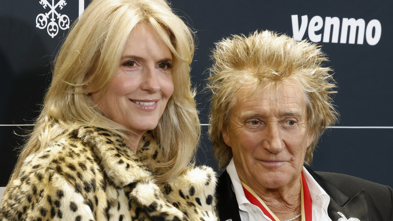 Penny Lancaster smiling in leopard print coat and Rod Stewart smirking