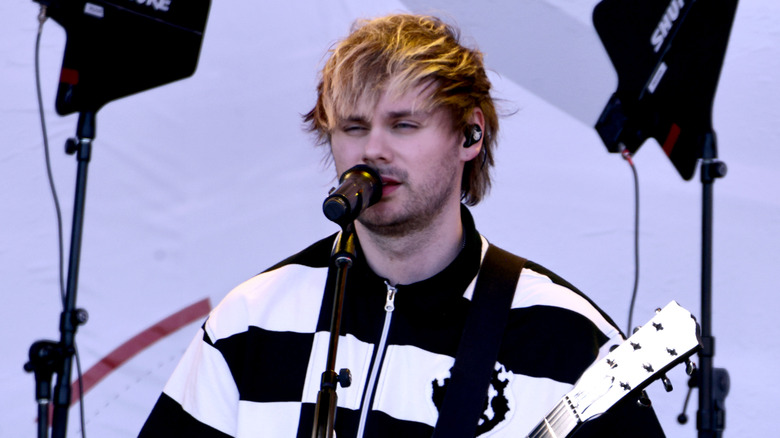 5 Seconds of Summer's Michael Clifford wearing a black-and-white striped shirt while performing onstage