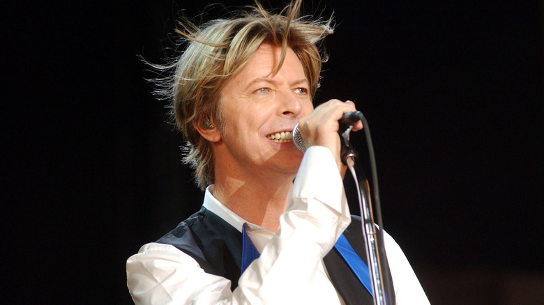 David Bowie singing on stage black background