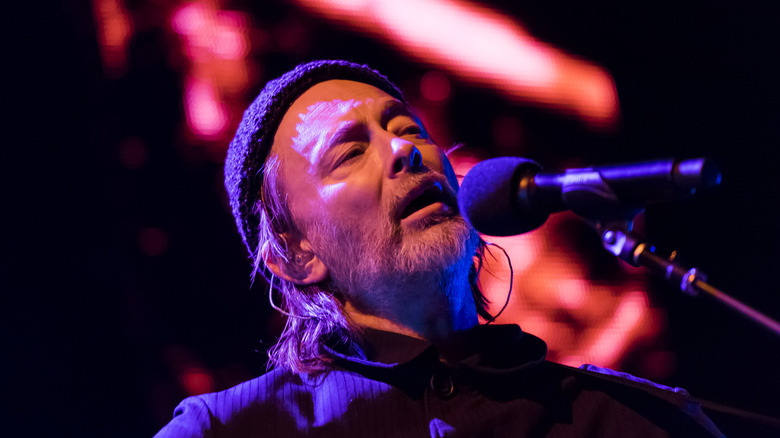 Thom Yorke wearing hat with beard singing on stage