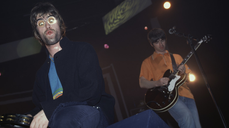 Liam and Noel Gallagher performing on stage with Oasis in 1996