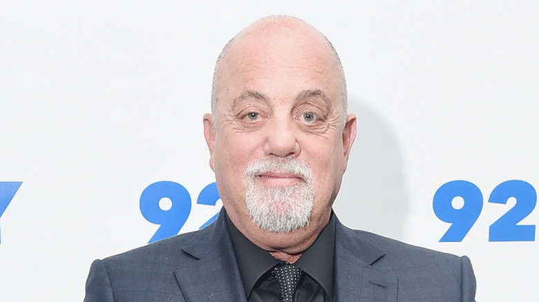 Billy Joel smiling in grey suit at event